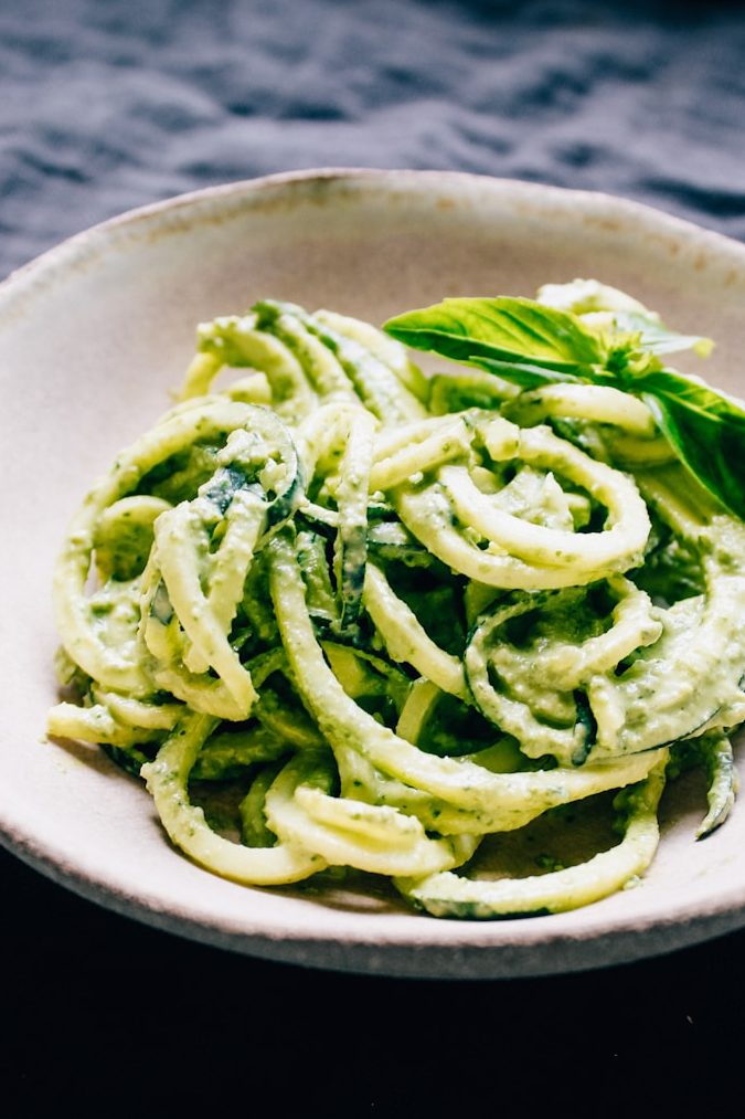 a white bowl filled with pesto pasta on top of a table